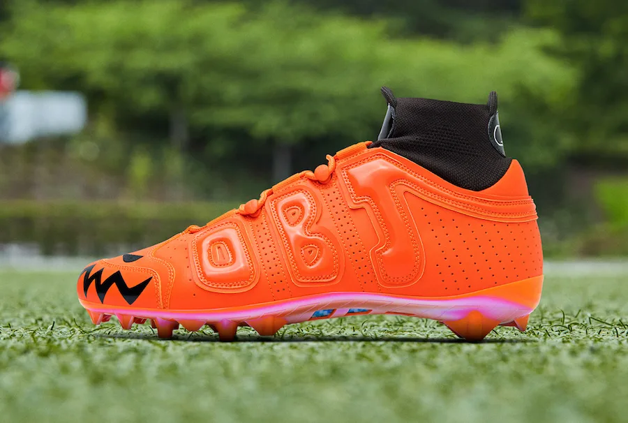 lateral view, orange upper with black 'OBJ' lettering, jack-o'-lantern toe design, OBJ Uptempo Cleat