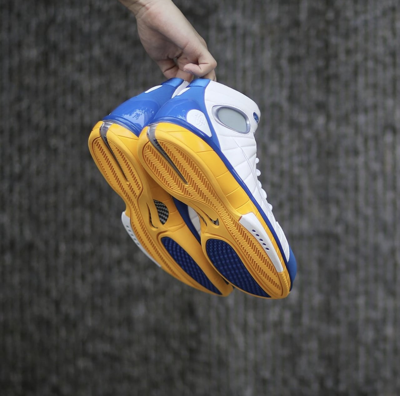 held pair showing yellow herringbone outsoles and blue heel patches, hand grips heel loops, Zoom Huarache 2K4