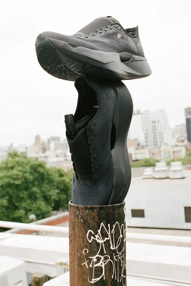 single shoe balanced sole-up on rusted graffiti pole against city rooftop skyline, Garments VECTIV Forward