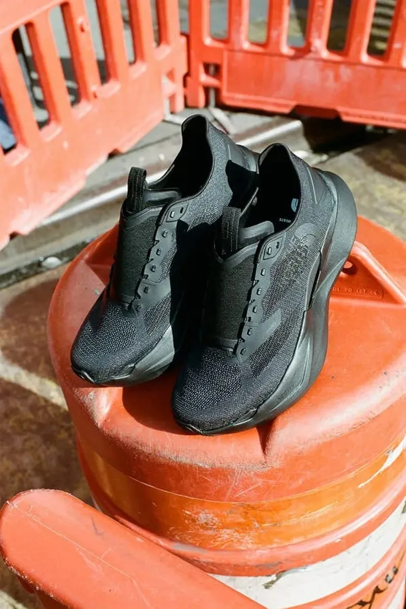 pair resting on orange traffic barrel, angled toe view with orange barriers behind, Garments VECTIV Forward