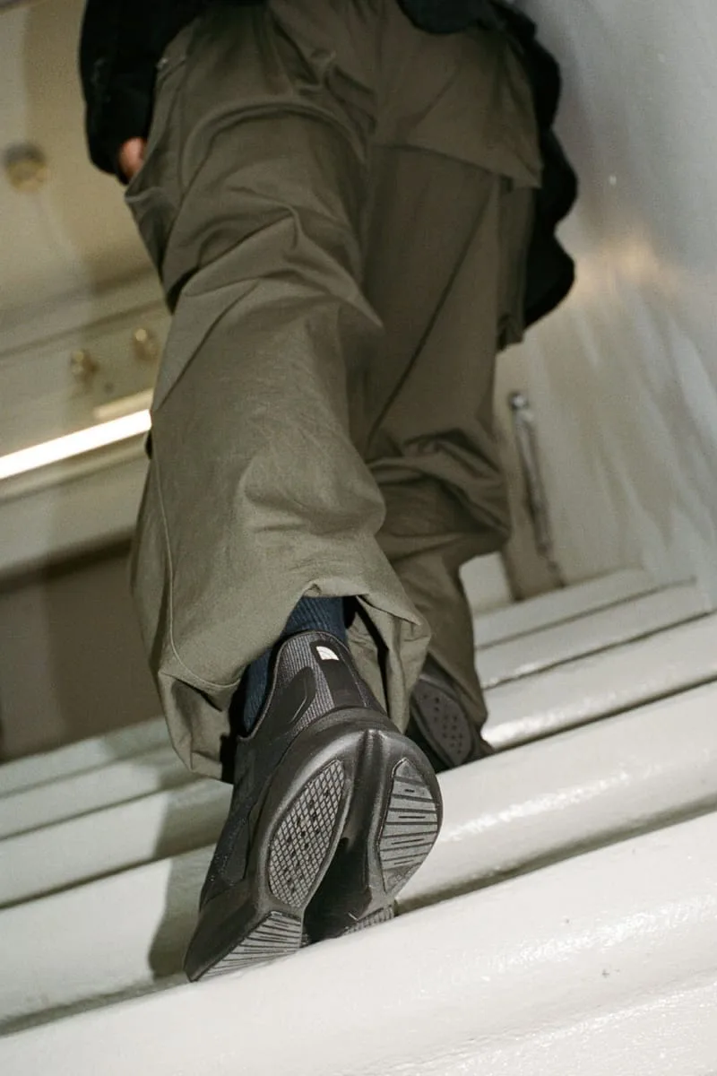 on-foot heel and outsole close-up on white stairs, olive trousers above, Garments VECTIV Forward