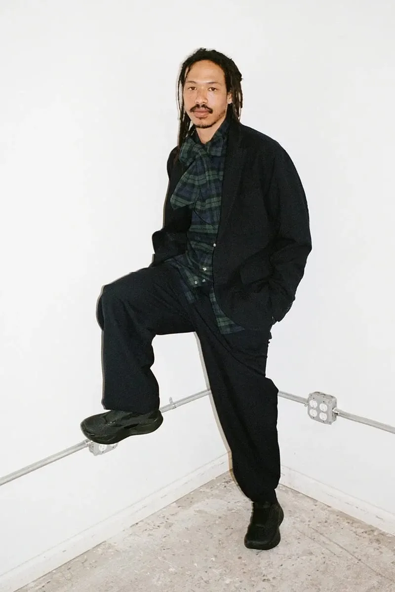 on-foot full body, man in black tailored fit balancing one foot on railing, Garments VECTIV Forward