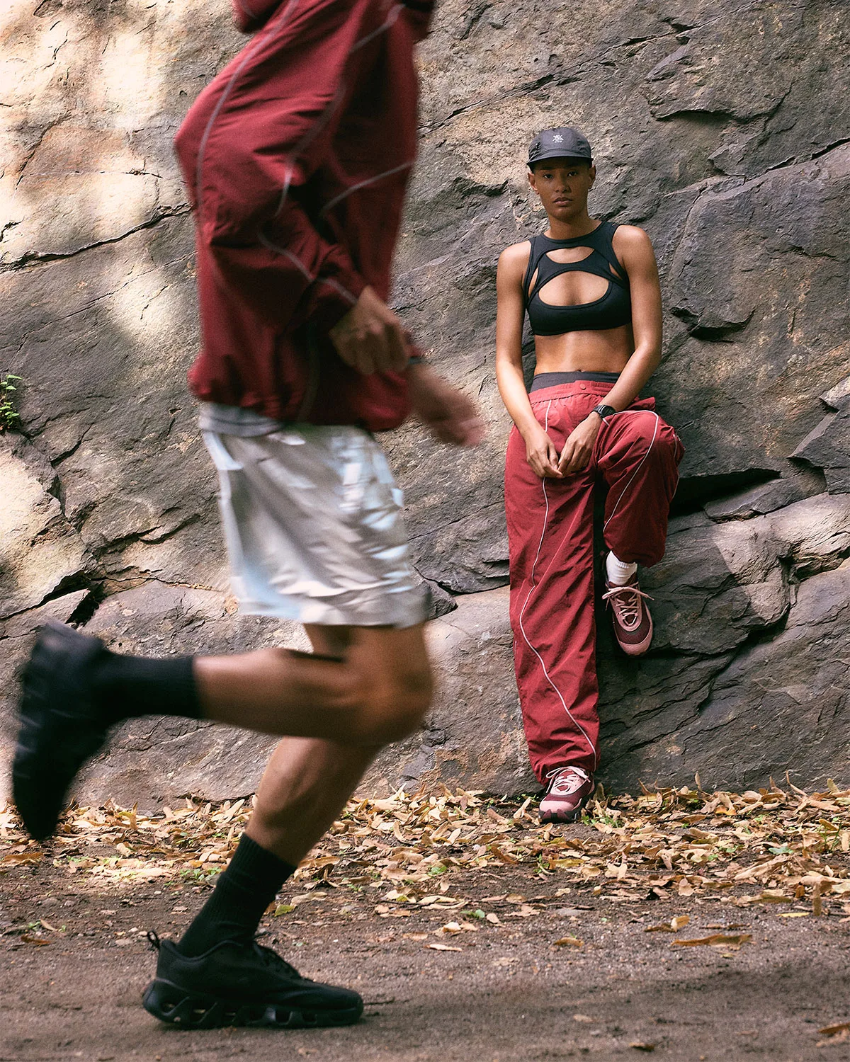 on-foot, woman in pink/burgundy pair leaning on rock wall, runner in black pair blurred, K Tech 3