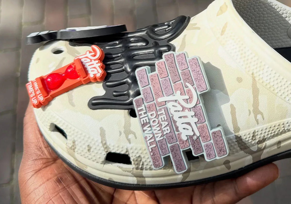 in-hand toe close-up showing Patta brick charm, black drip graphic and red hourglass charm, Clog x Patta
