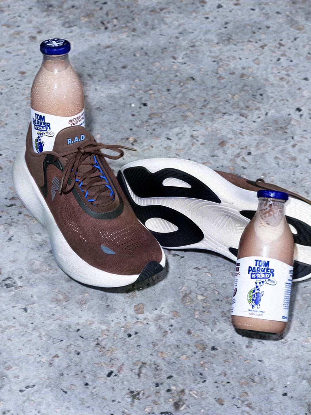 lateral pair on concrete floor, brown suede upper, blue laces, milk bottle in toe box, Choccy Milk
