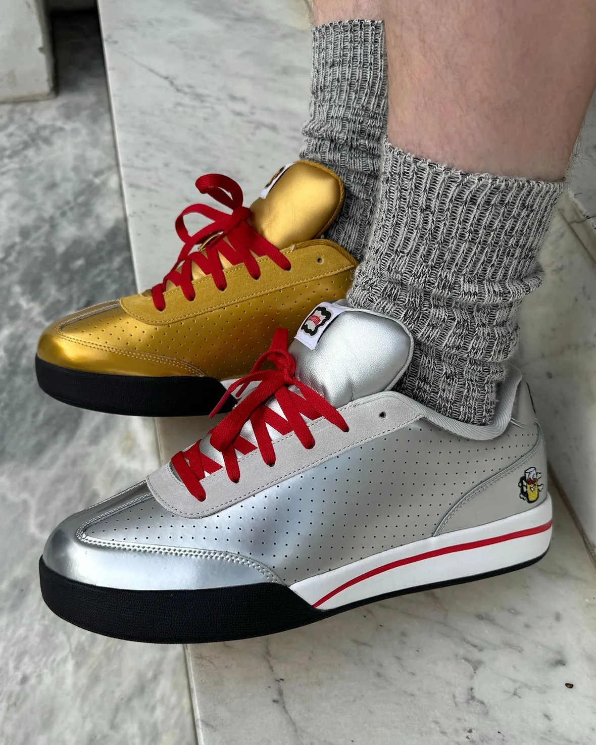 on-foot lateral, gold and silver sneakers with red laces, grey ribbed socks, Japanese Beer Pack