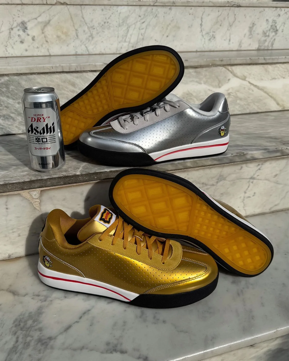 outsole view, silver and gold pairs with yellow waffle soles, Asahi can beside, Japanese Beer Pack
