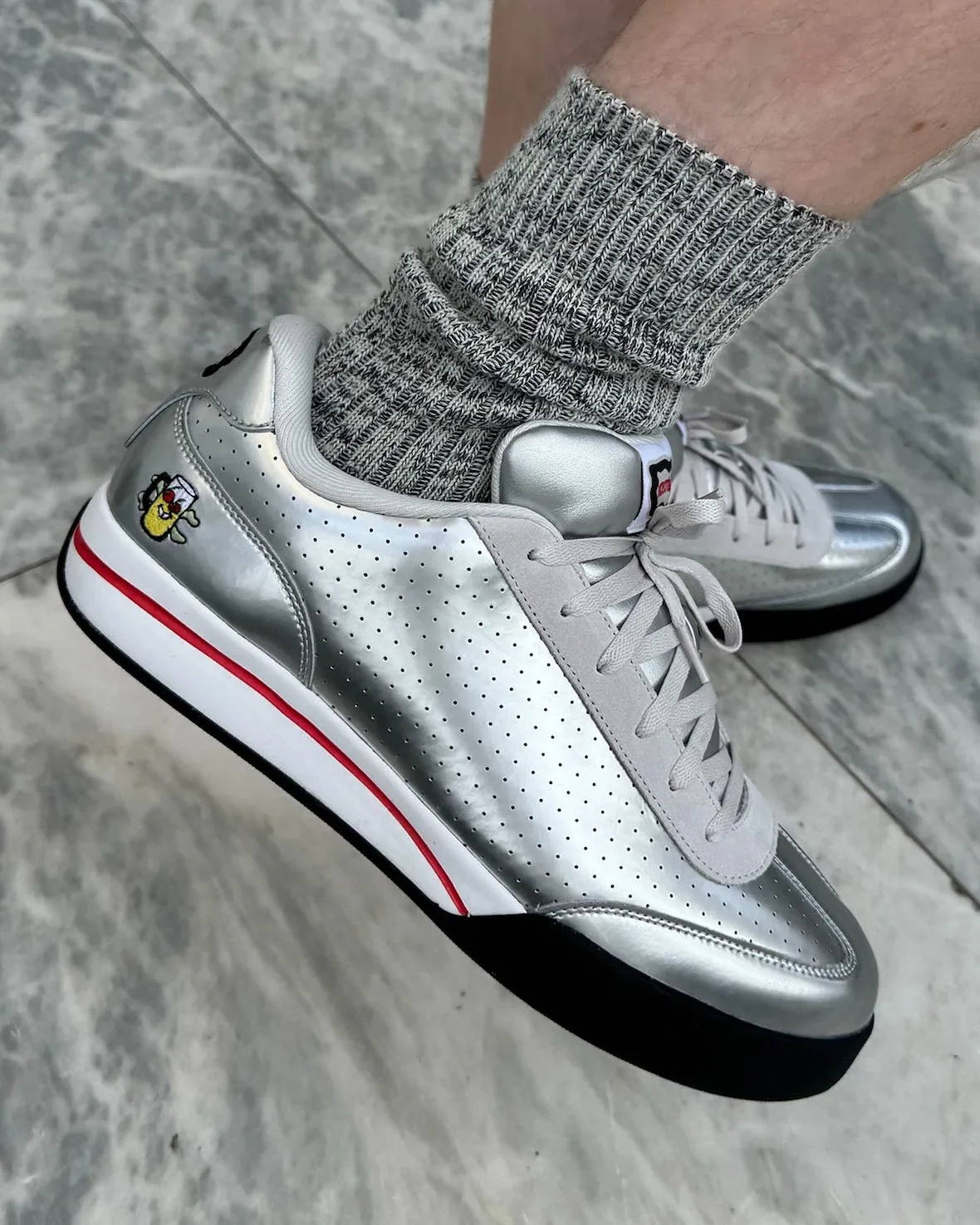on-foot lateral close-up, silver sneaker, ribbed grey socks, mug logo, Japanese Beer Pack