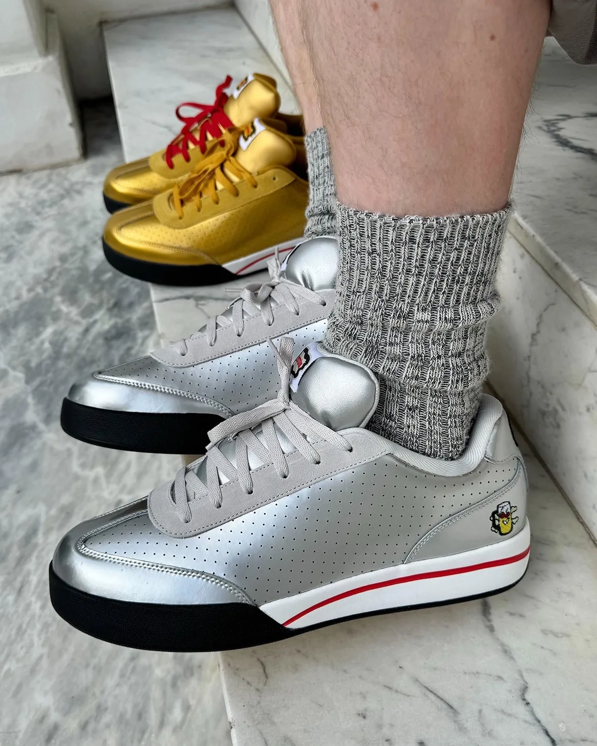 on-foot lateral, silver sneaker with gold pair blurred behind, grey socks, Japanese Beer Pack