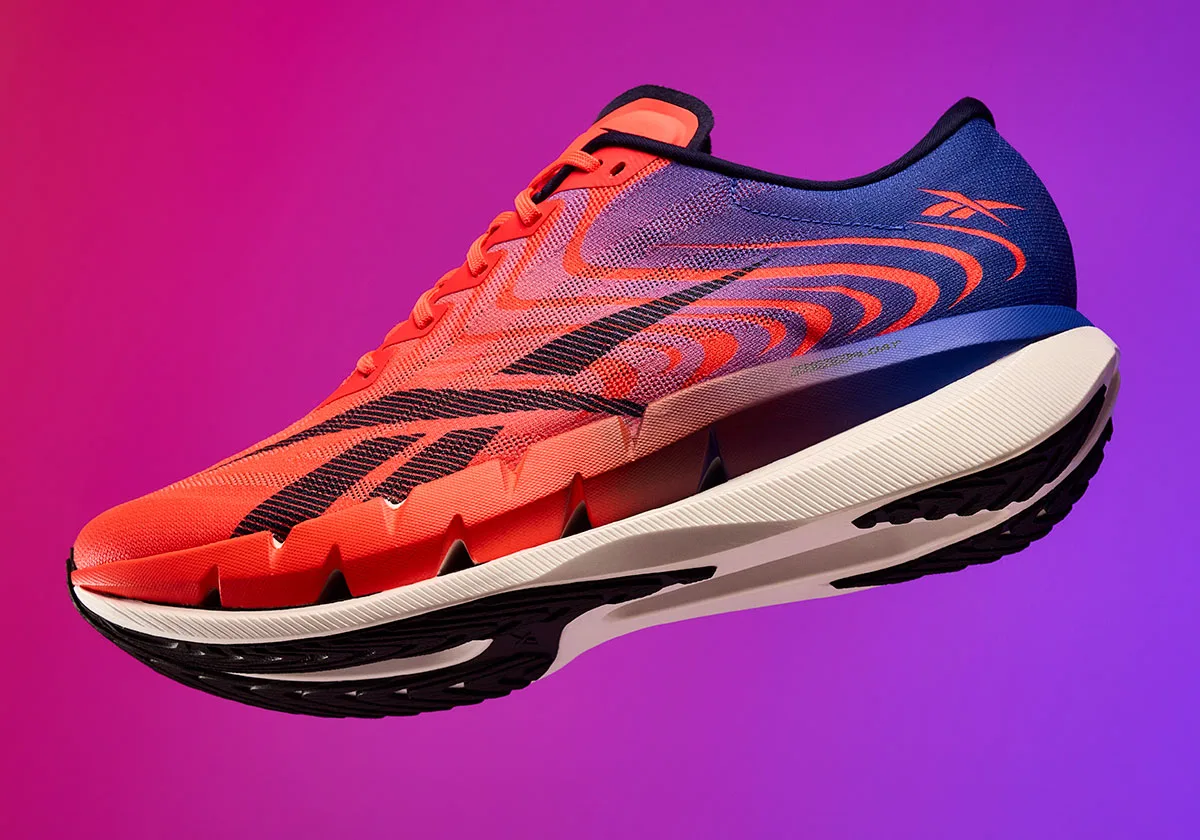 lateral view, orange-to-blue gradient upper on white cushioned midsole, purple background, Reebok SpeedShifter