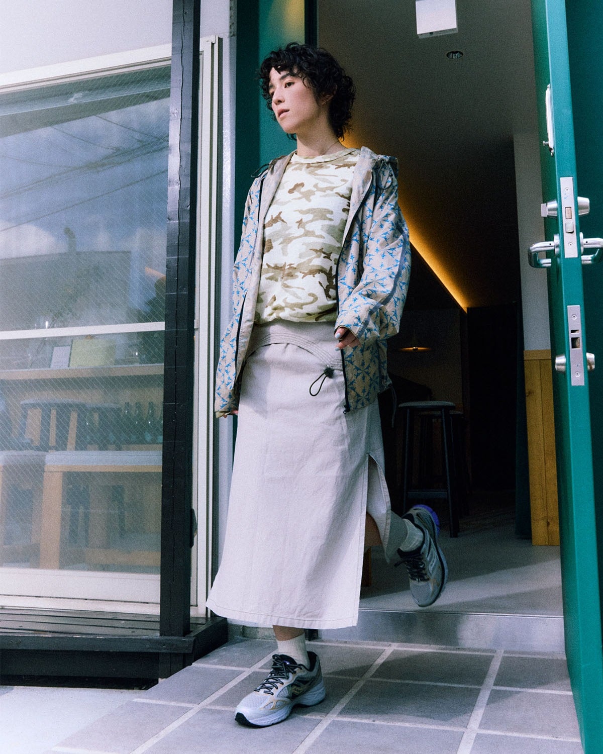 on-foot lateral view, grey mesh sneaker worn with cream skirt in doorway, Daikanyama Capsule Collection