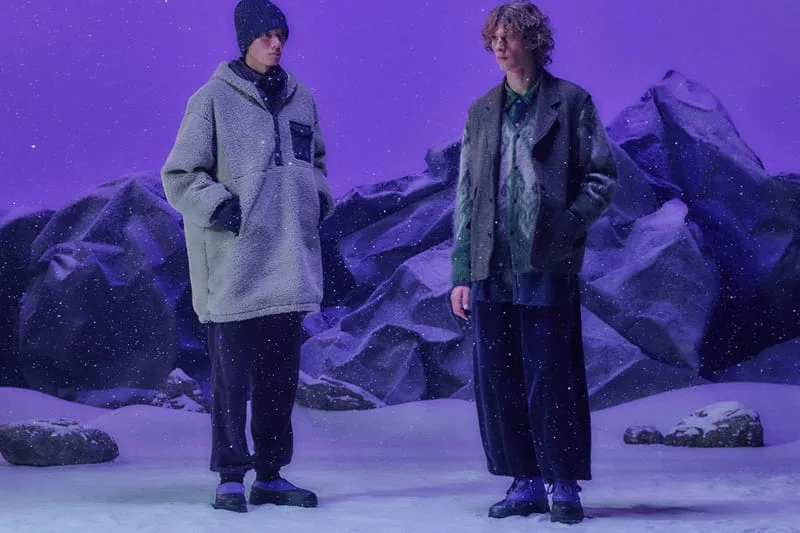 Two models standing in snowy rocky scene wearing purple duck boots with outerwear, NEEDLES Ambler Collection