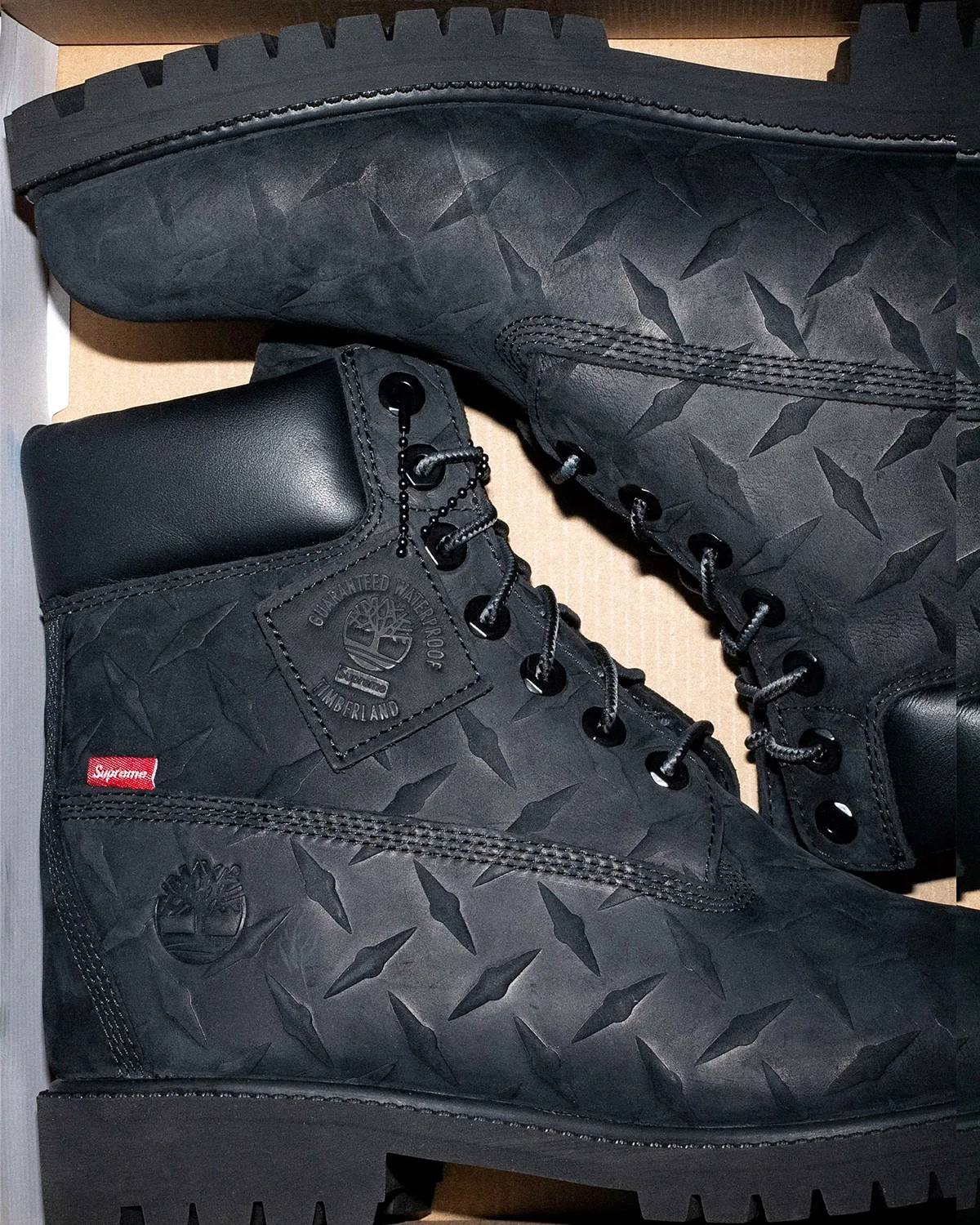 close-up lateral view of black diamond-plate boot with red Supreme tab, Premium Waterproof Boot