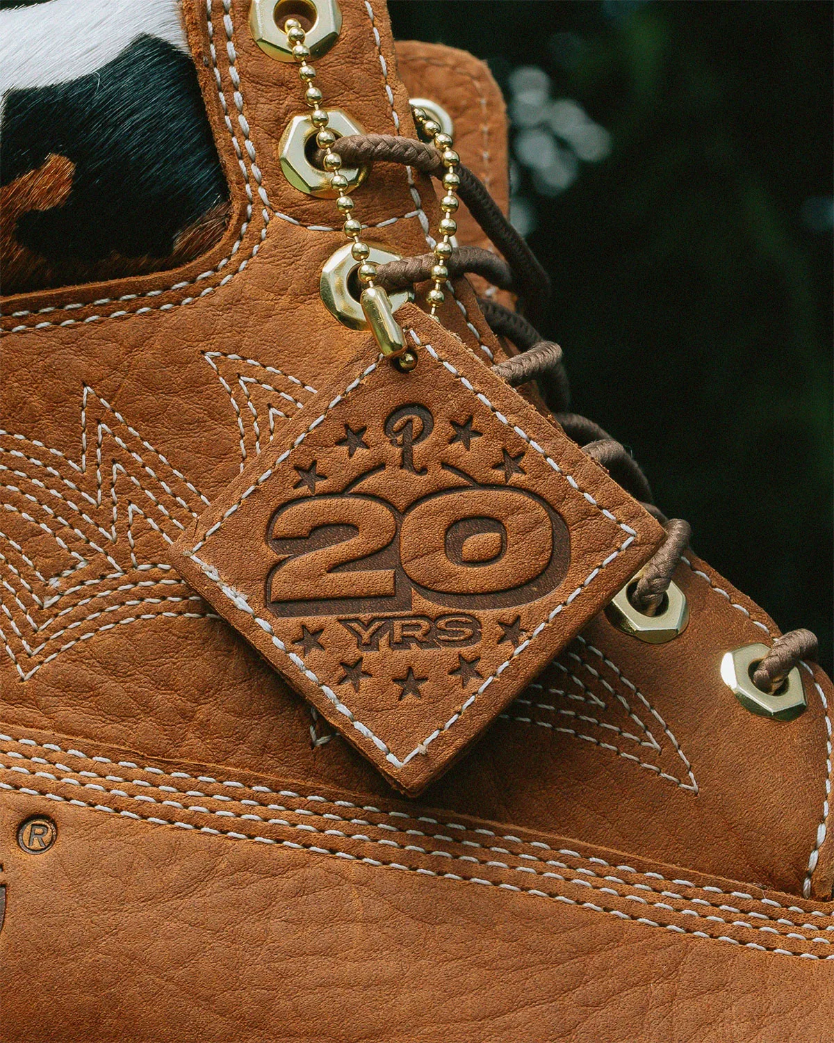 close-up of wheat boot, embossed 20-year tag, cow-print collar visible, x Sneaker Politics