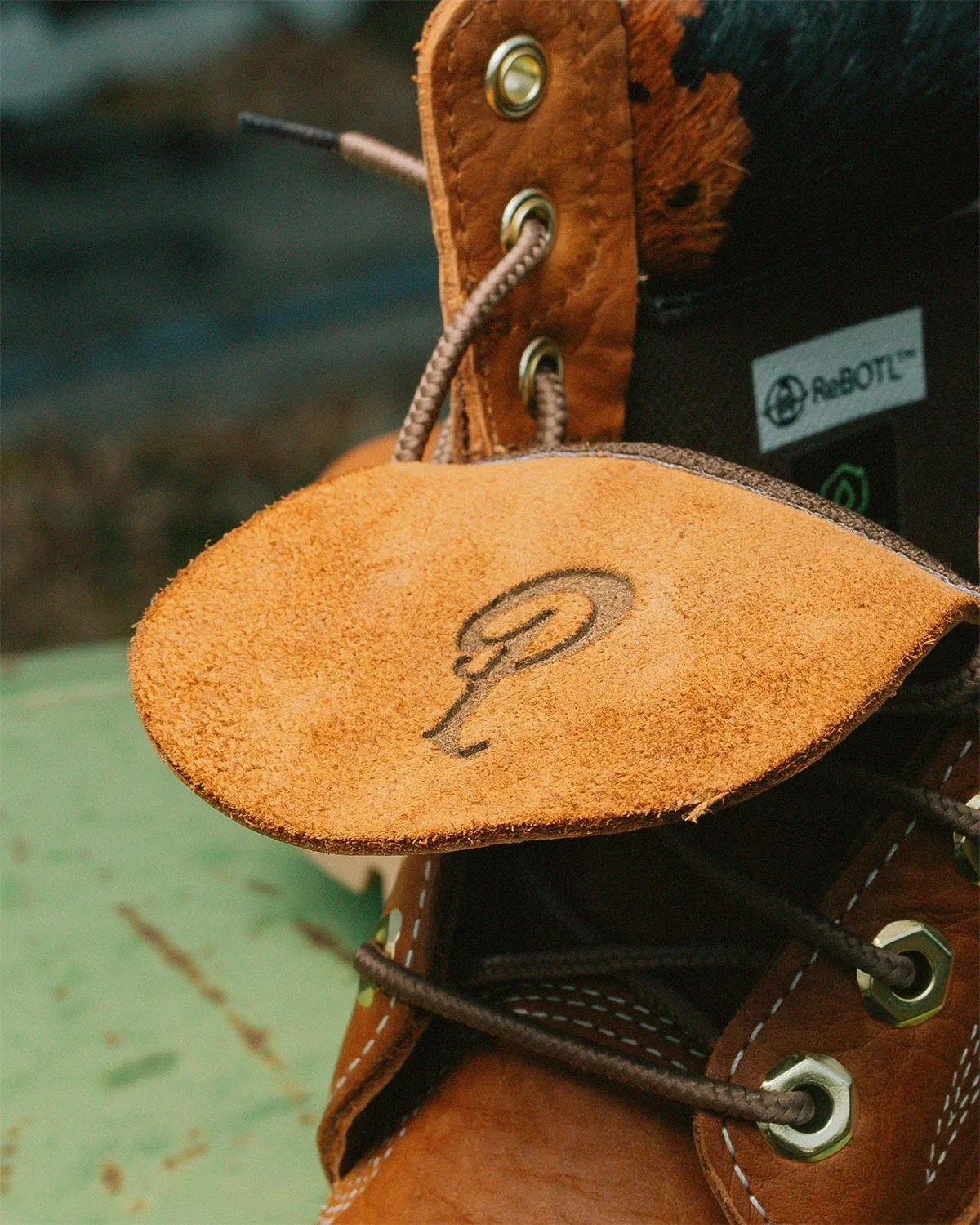 close-up of tan Sneaker Politics logo tag with cow-print collar behind, x Sneaker Politics