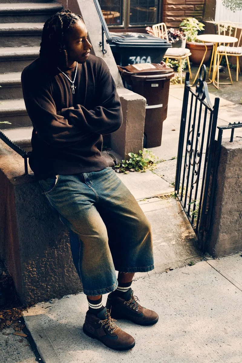 on-foot full body, man seated near gate, boots with orange laces, Timberland Field Boot