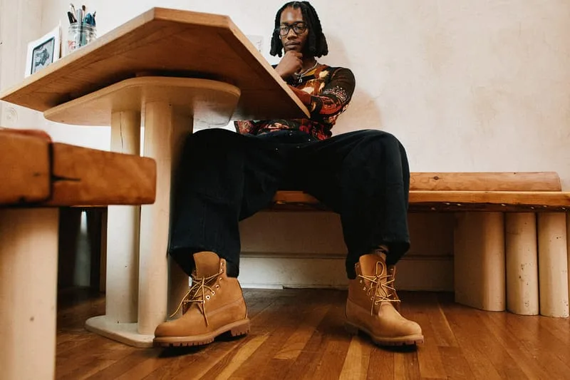 on-foot under table, tan nubuck boots with orange laces on wood floor, Timberland Field Boot