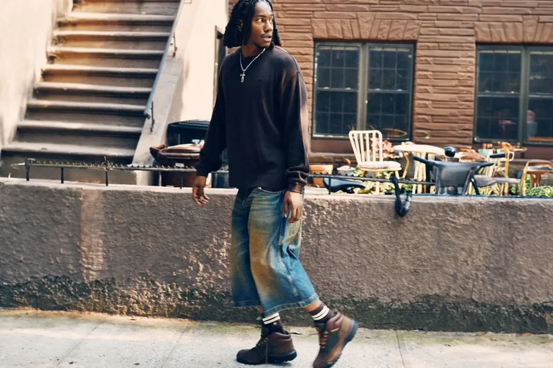 on-foot side view, man walking past brownstone with cropped denim, Timberland Field Boot
