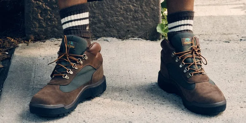 close-up on-foot pair, orange laces and green heel panel, ribbed socks, Timberland Field Boot