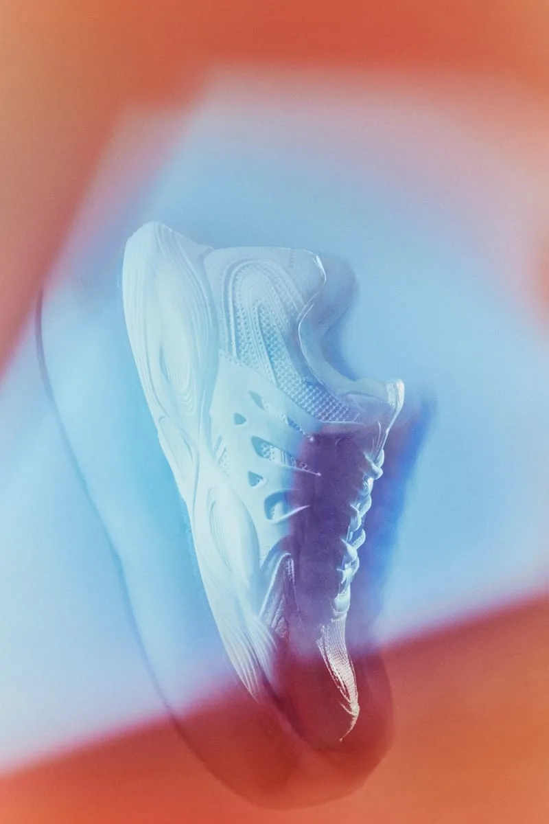 blurred lateral close-up, pale blue mesh panels over a wavy white midsole, Tomorrowland WR1