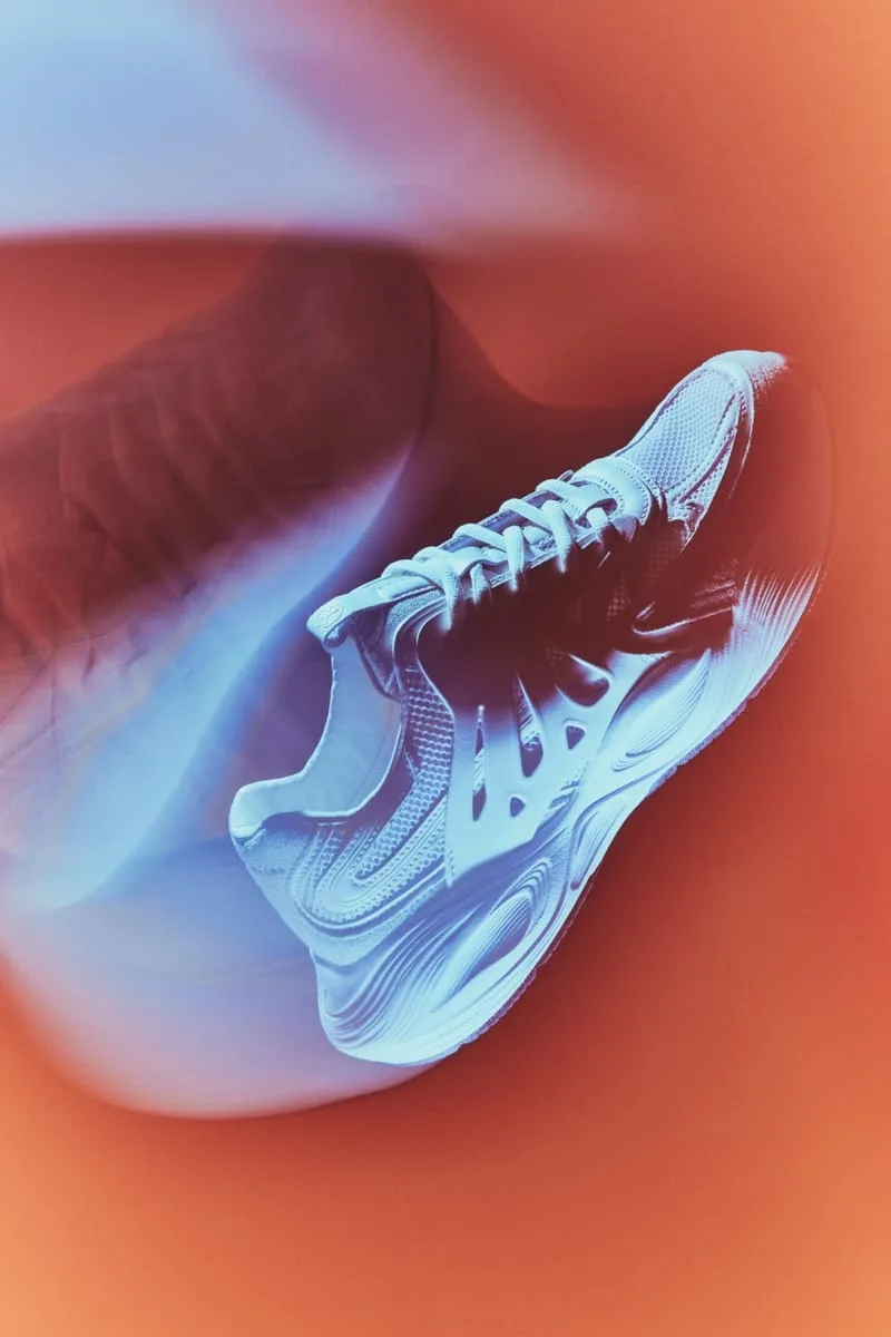 motion-blurred lateral view, pale blue mesh and ridged white sole, orange background, Tomorrowland WR1