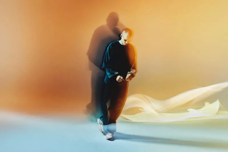 on-foot lateral view, white and grey pair worn with black trousers, orange-blue backdrop, Tomorrowland WR1