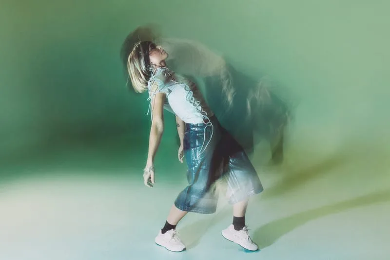 on-foot side view, white pair worn with a corset top, green backdrop, motion blur, Tomorrowland WR1
