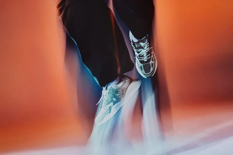 on-foot close-up, pale sneakers in motion on both feet, orange blurred backdrop, Tomorrowland WR1