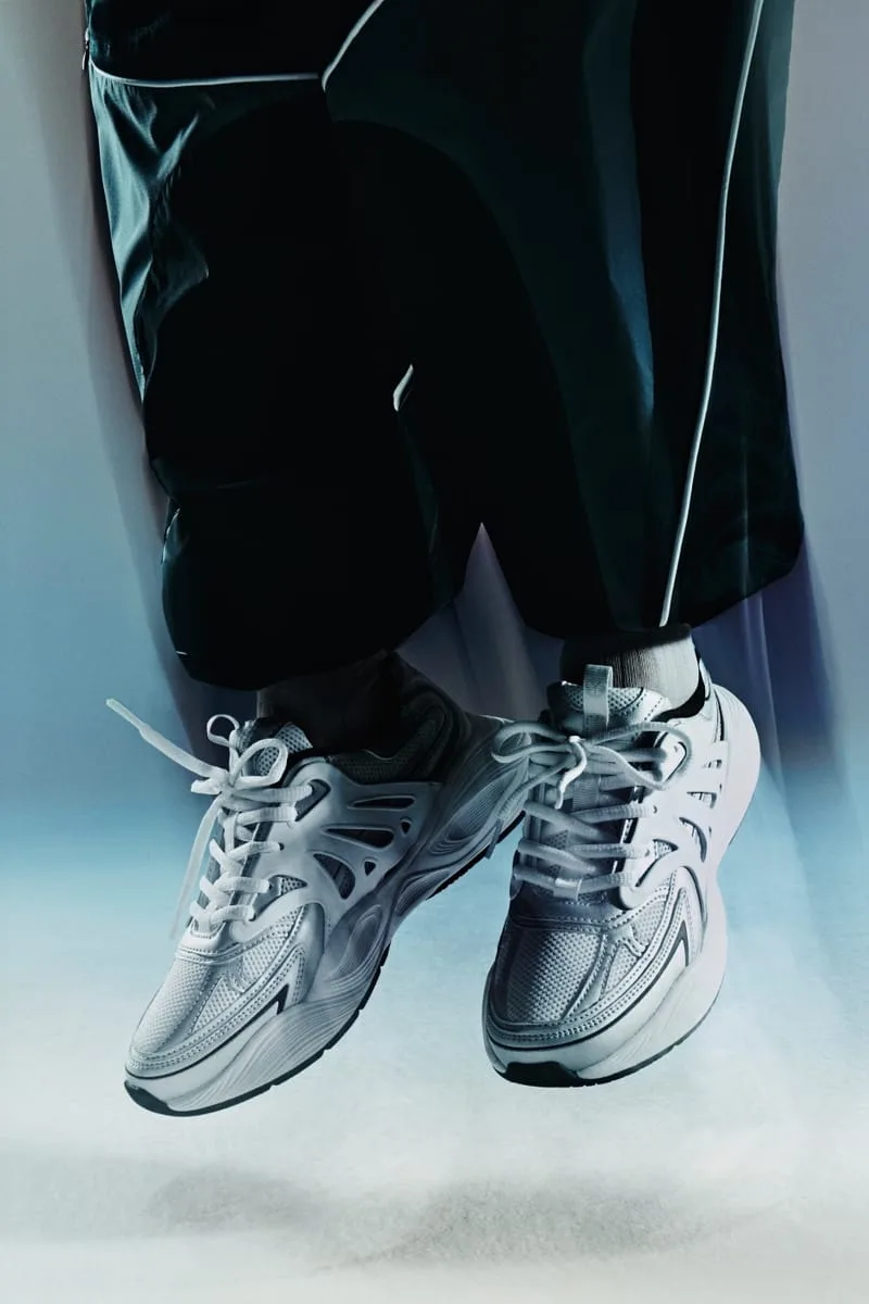 on-foot close-up, white and grey pair dangling below black wide-leg trousers, Tomorrowland WR1