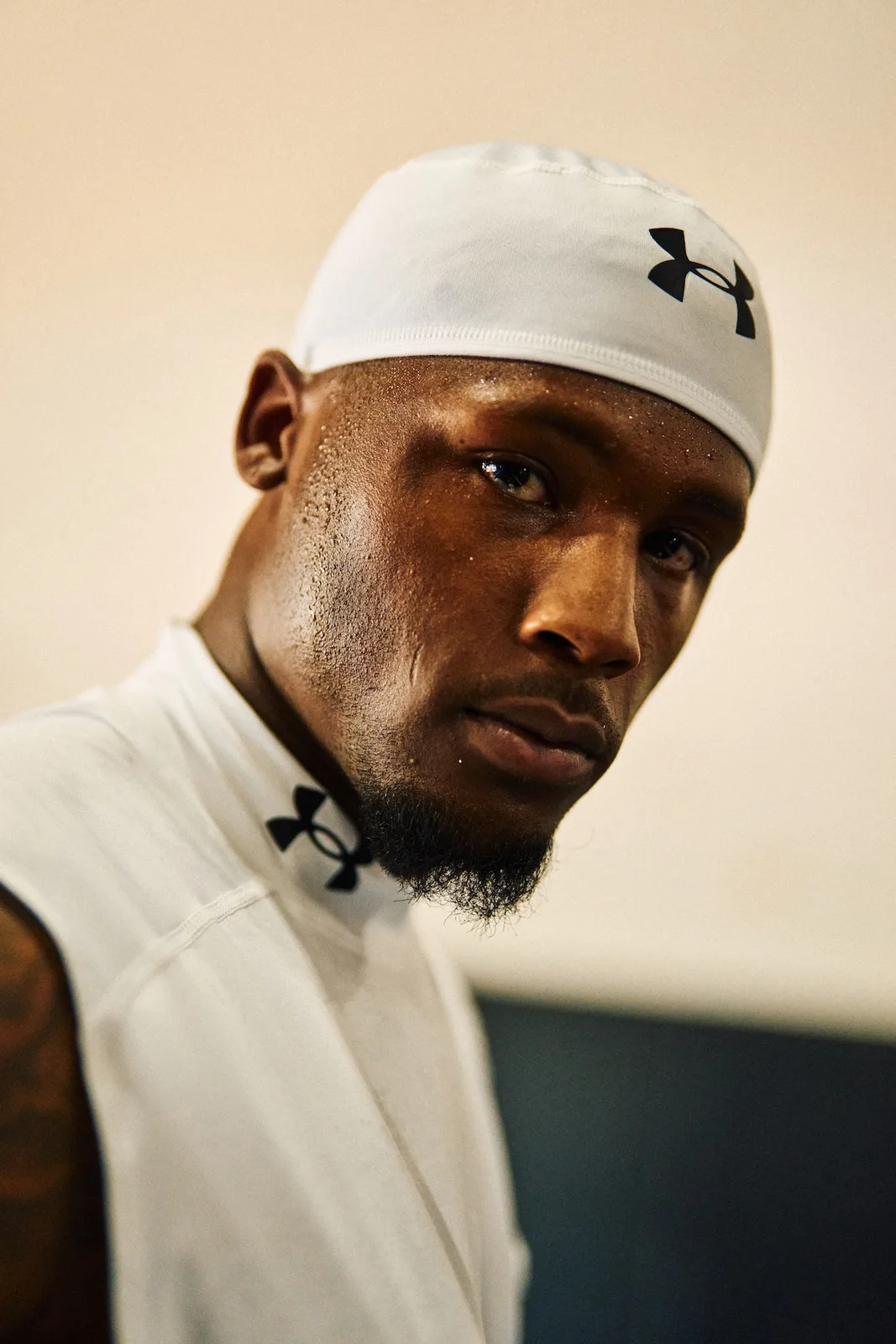 low-angle close-up, white skull cap and top with black Under Armour logos, x Under Armour