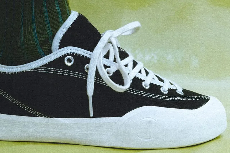 on-foot toe close-up, black and white shoe with white laces, green striped sock, VILLAGE PM 2PM