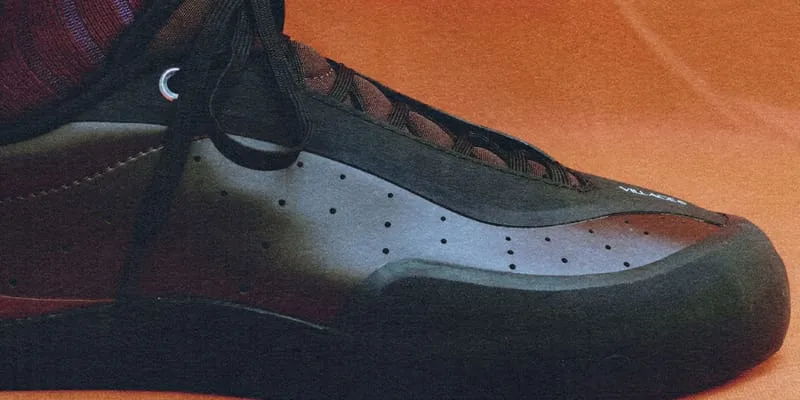 on-foot medial close-up, grey and burgundy dotted toe panel, orange backdrop, VILLAGE PM 2PM