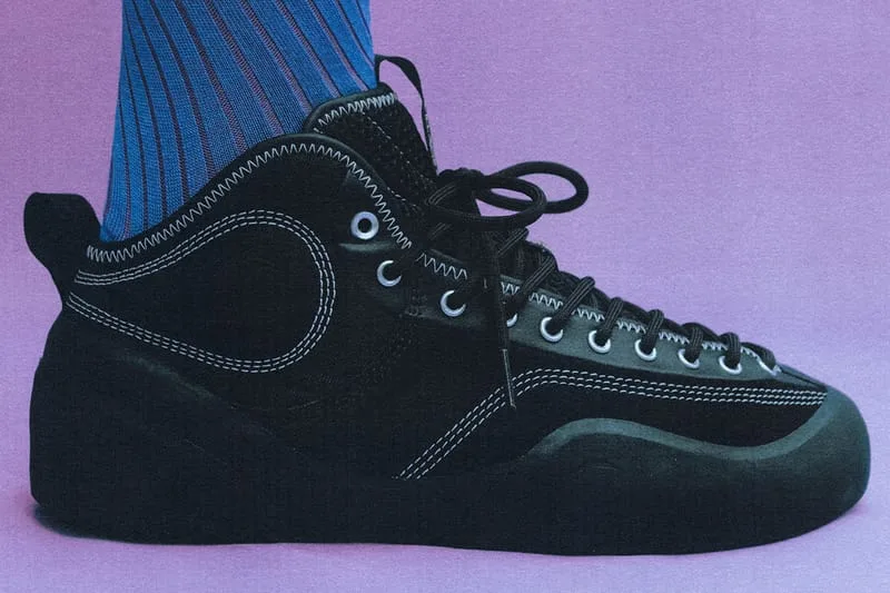 on-foot lateral view, black suede shoe with blue striped sock, purple backdrop, VILLAGE PM 2PM