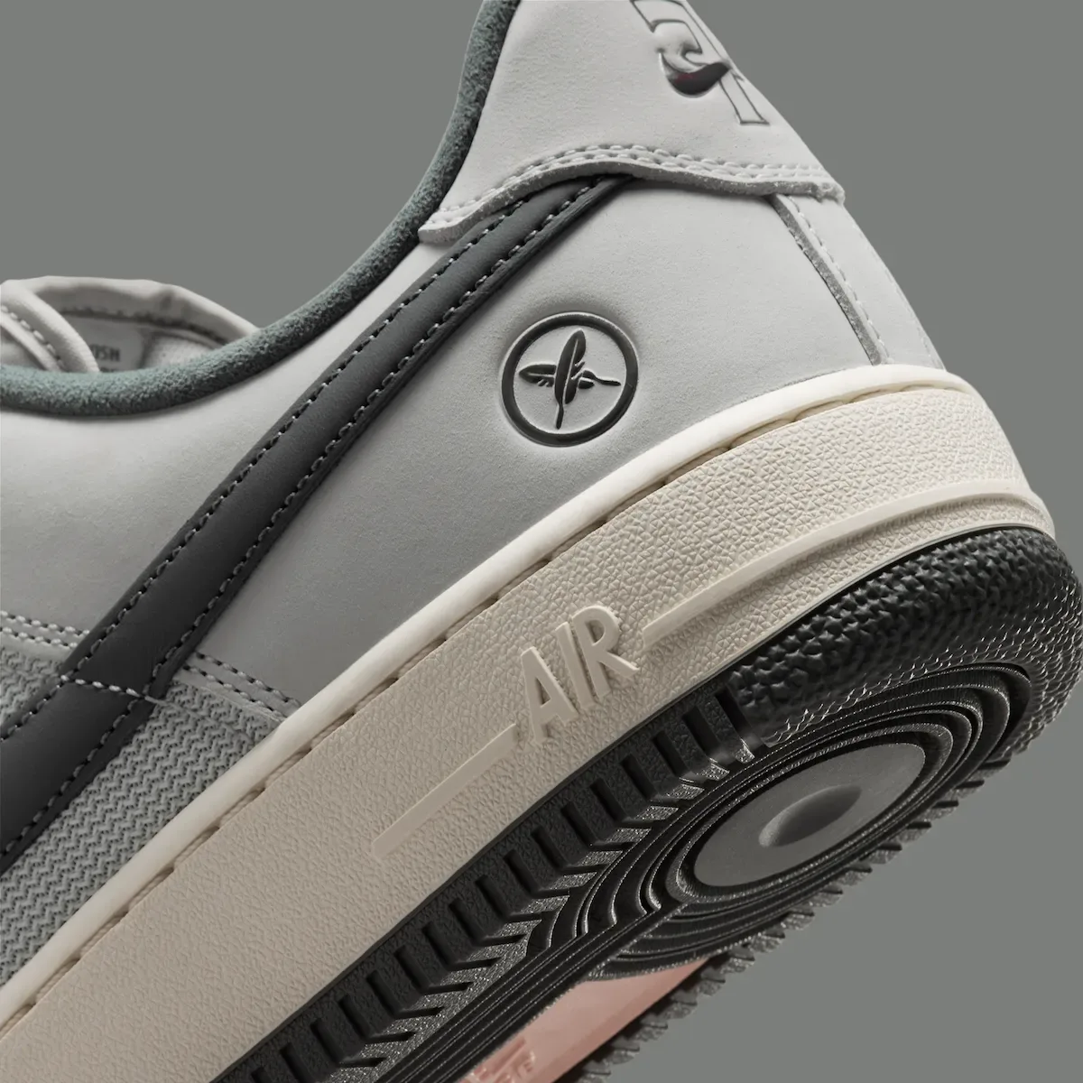 close-up heel detail, X logo circle above cream midsole reading AIR, Iron Grey
