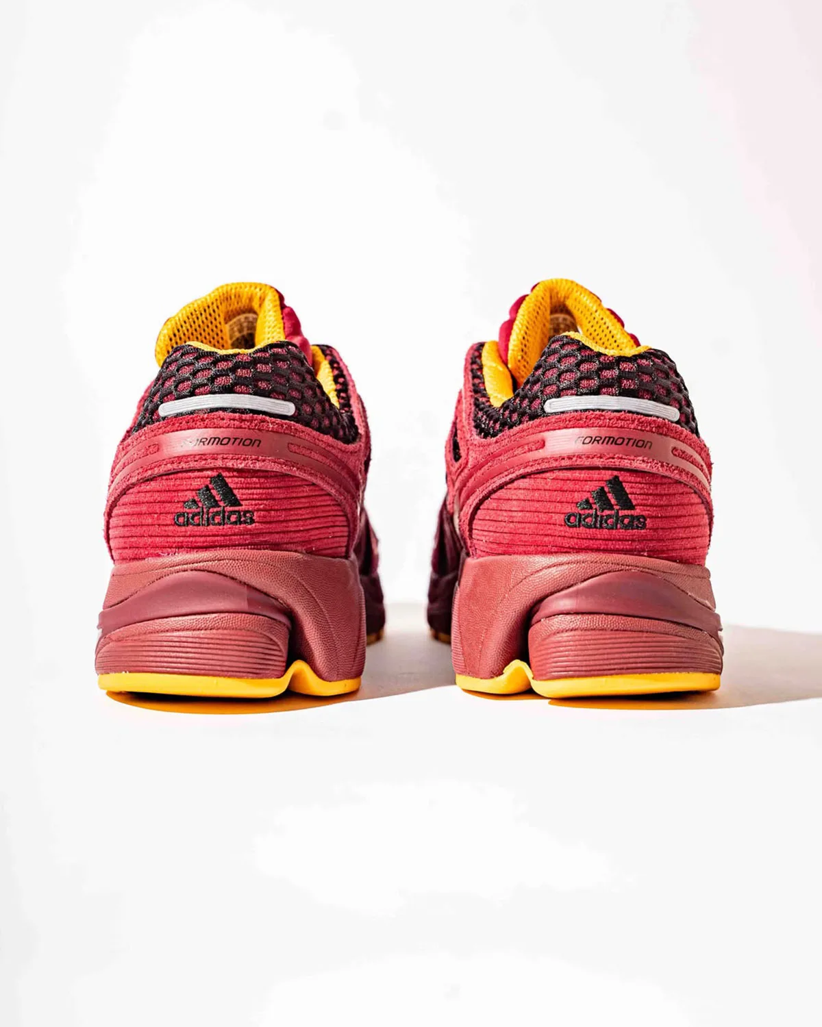 Heel view of a pair, burgundy corduroy-like heel panels, black adidas logos, yellow midsole edge, x Deadstock Coffee