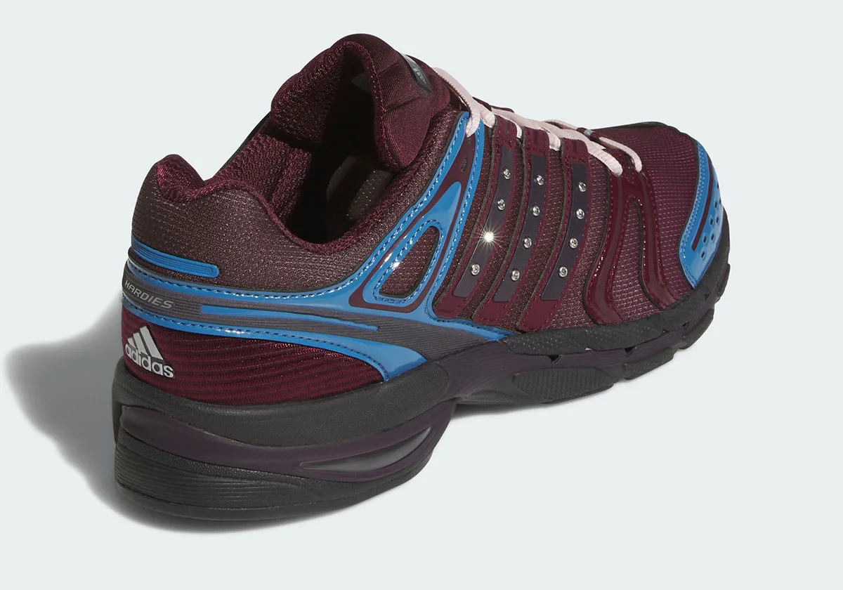 Rear three-quarter view showing Hardies text, white adidas logo, blue heel overlays, black midsole, 5 x Hardies