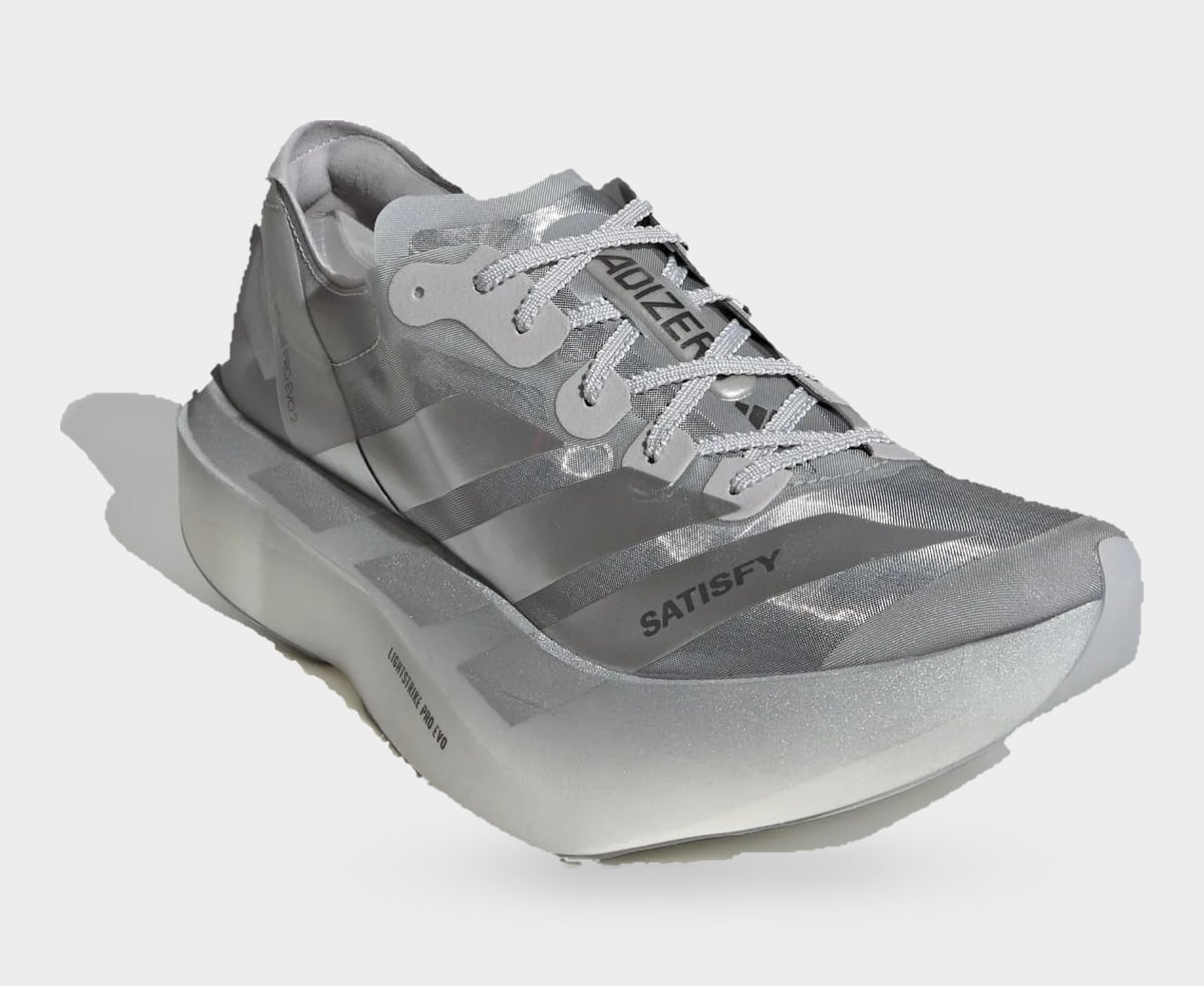 Three-quarter toe view of silver shoe with grey laces and SATISFY on the side, 2 x Satisfy