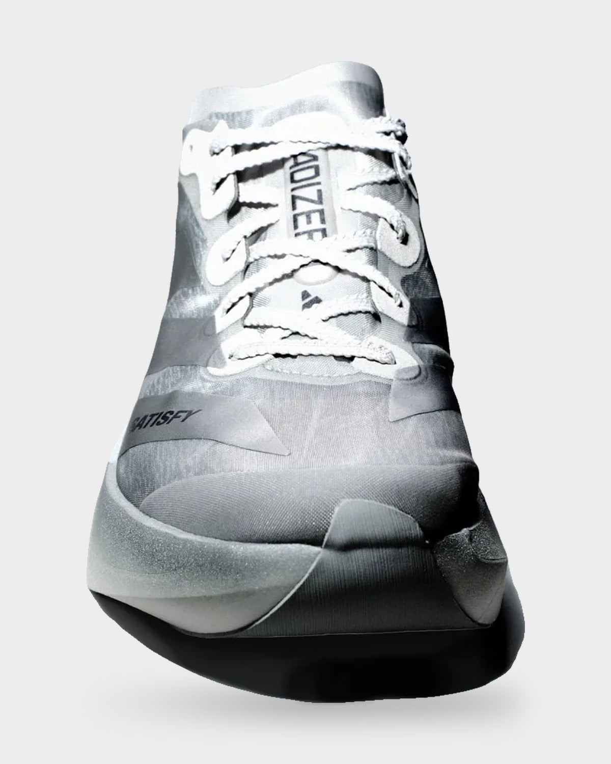 Front toe-on view of silver shoe with white laces and dramatic dark shadow, 2 x Satisfy