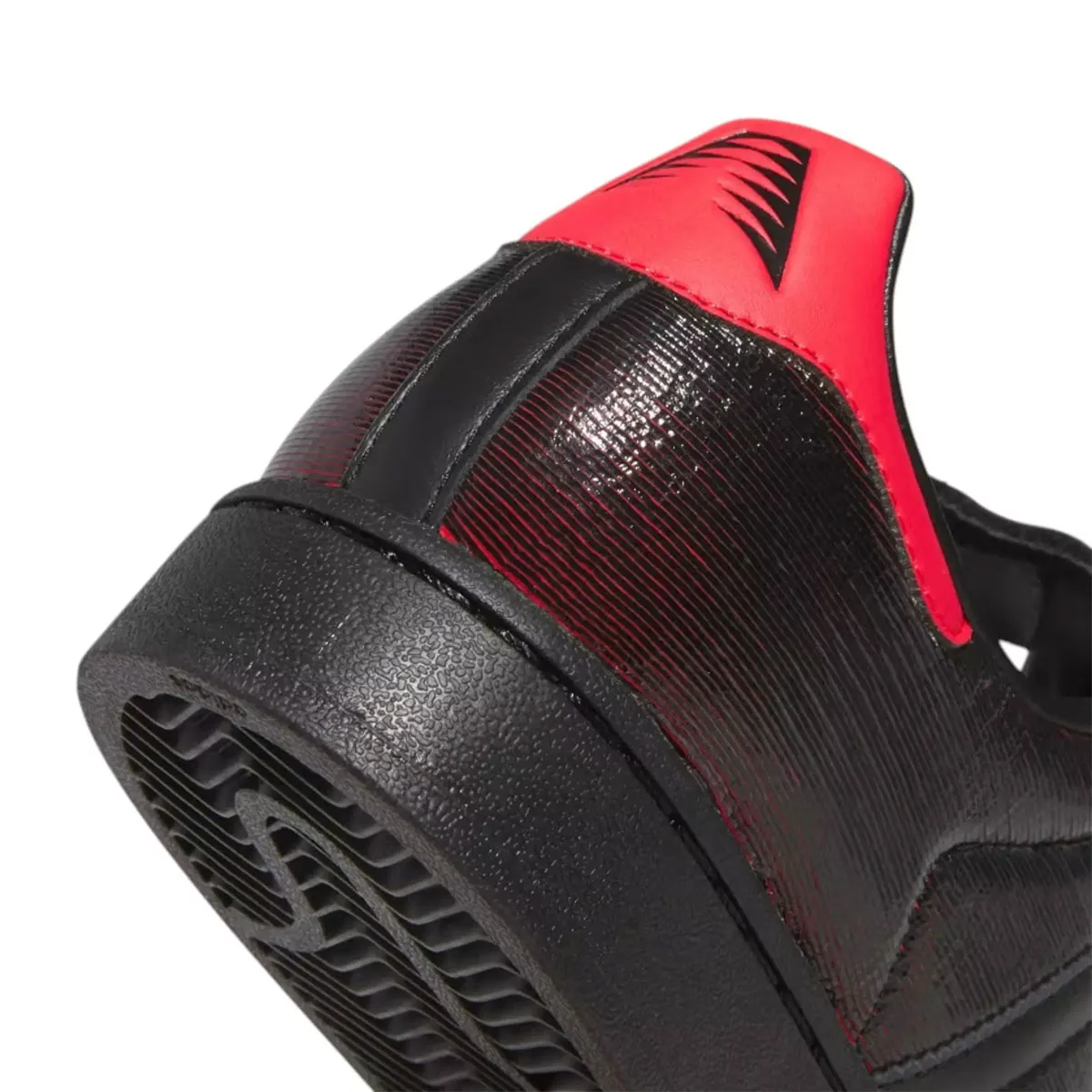 Detail of heel: red tab with black claw-mark logo, glossy ridged black upper, textured black midsole, on white, Halloween