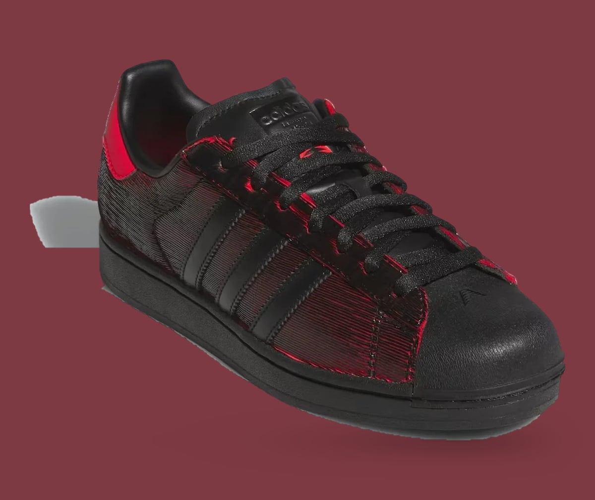 Single shoe, three-quarter front on maroon: black laces, shell toe with small logo, red-edged upper, Halloween