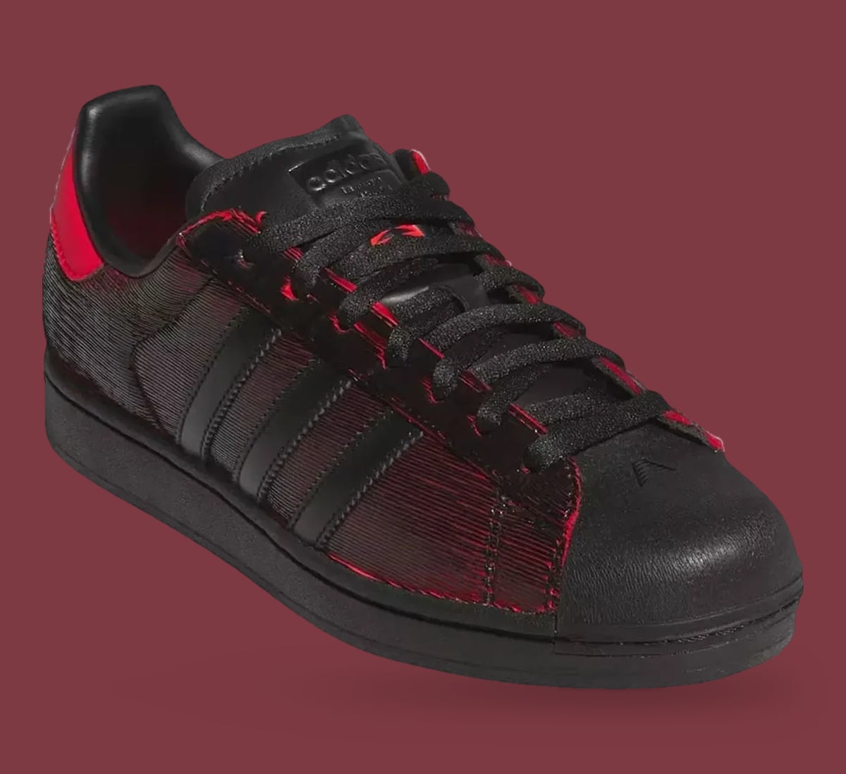 Single shoe, three-quarter front: black shell toe, black laces, red-edged ridged panels, adidas tongue label, Halloween