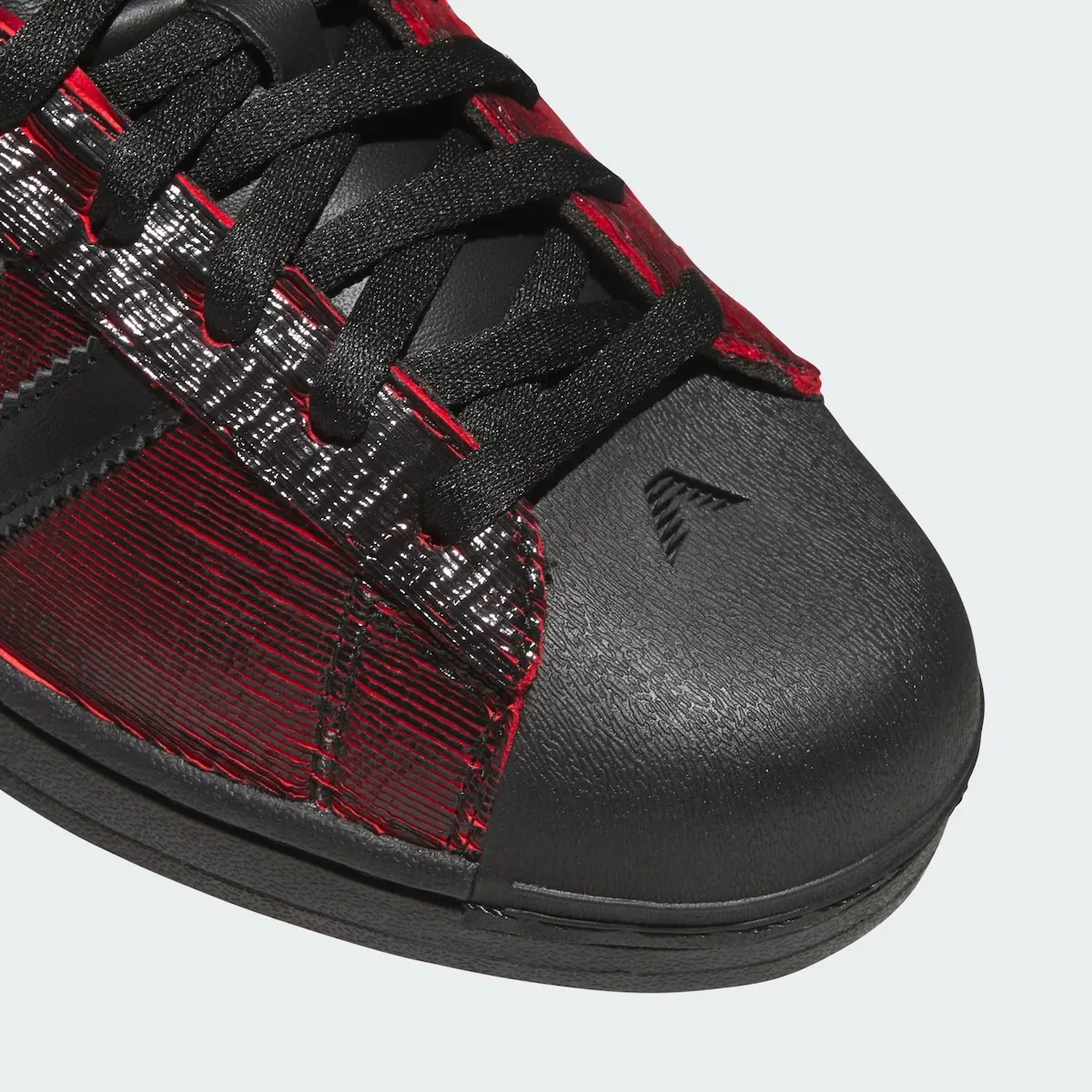 Toe detail: black shell toe with small embossed logo, black laces, glossy silver-black and red ridged panel, Halloween