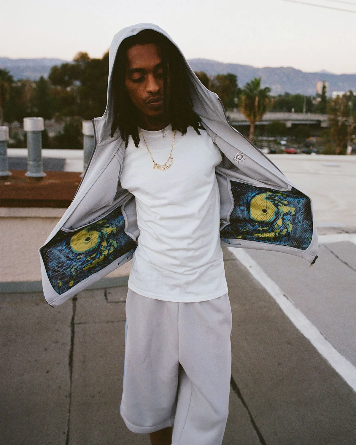 Person on rooftop holding open grey hoodie to show blue and yellow printed inner lining, Climacool x ADWYSD