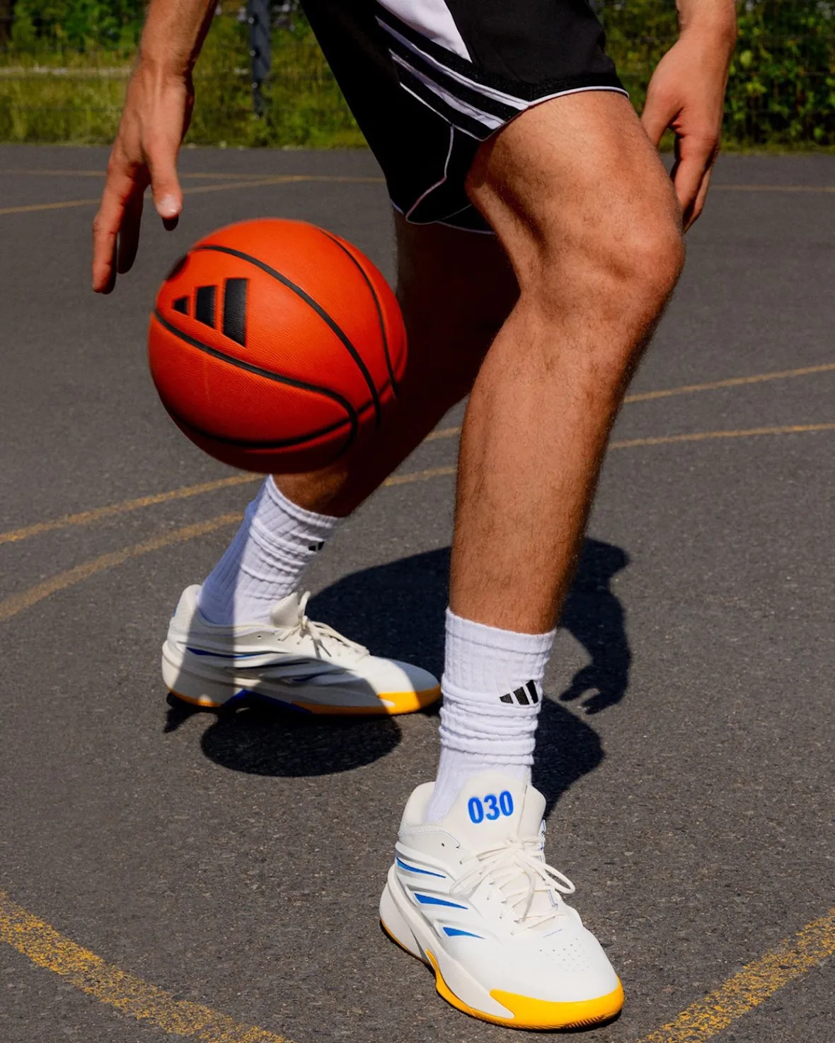 Close-up of a player dribbling an orange basketball, white 030 sneaker with yellow sole on court, Wagner Brothers