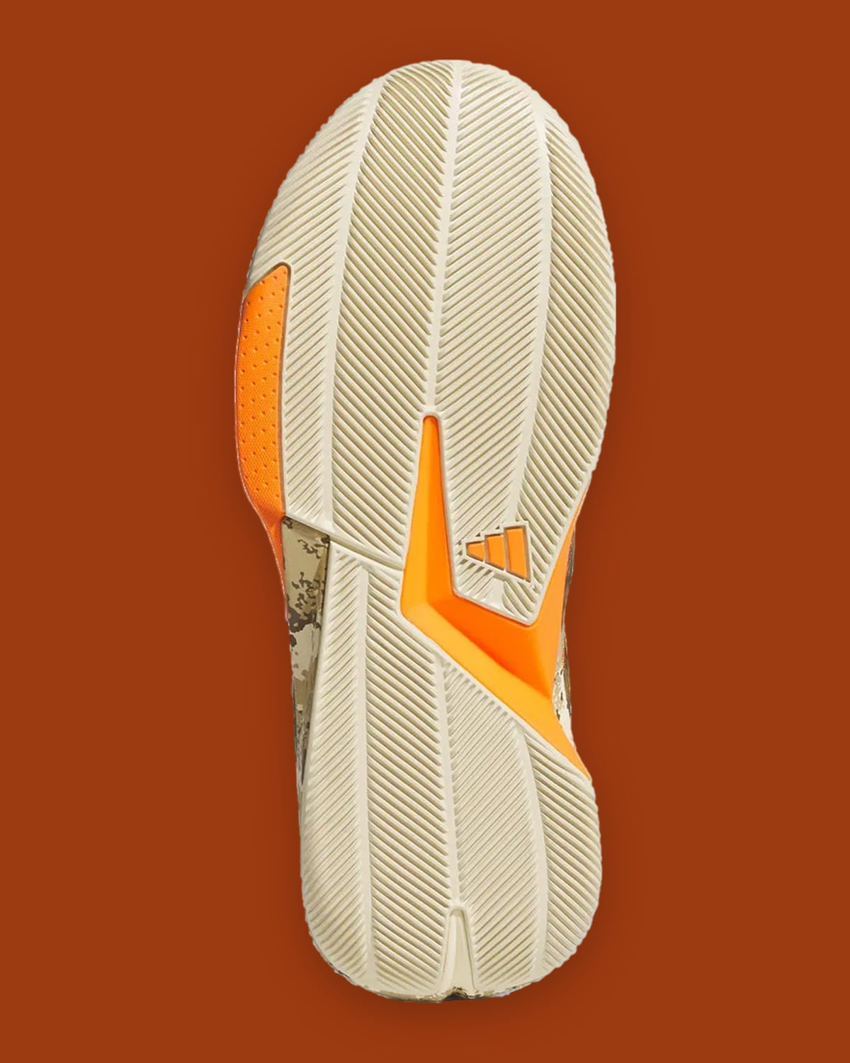 Outsole view in cream with herringbone tread, orange inserts and small three-stripe logo, What The Camo