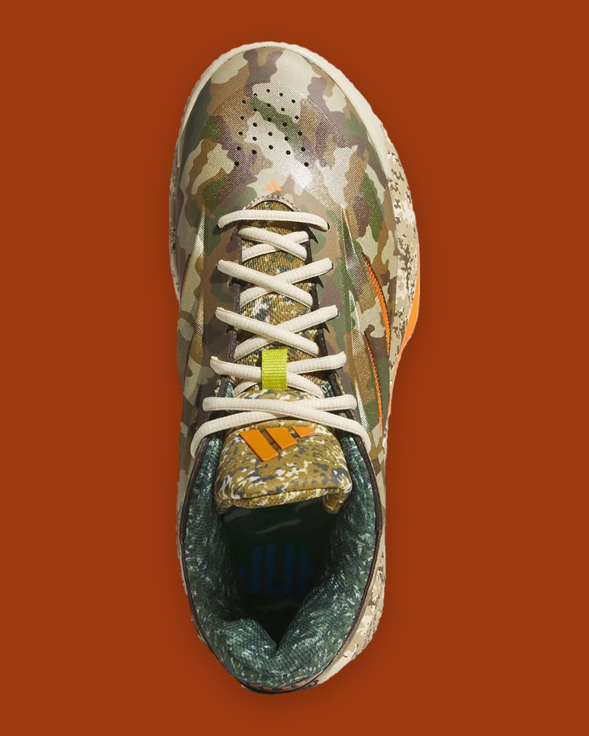 Top-down view of cream laces, lime lace loop and orange logo on camo tongue, What The Camo