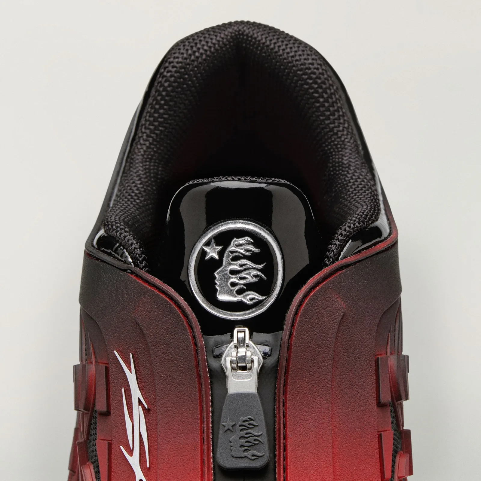 Detail of collar and zip pull with silver flame-head badge on black patent tab, Red/Black