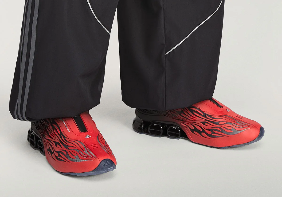 On-foot view of both shoes under black trousers with grey stripes, red flame uppers, Red/Black