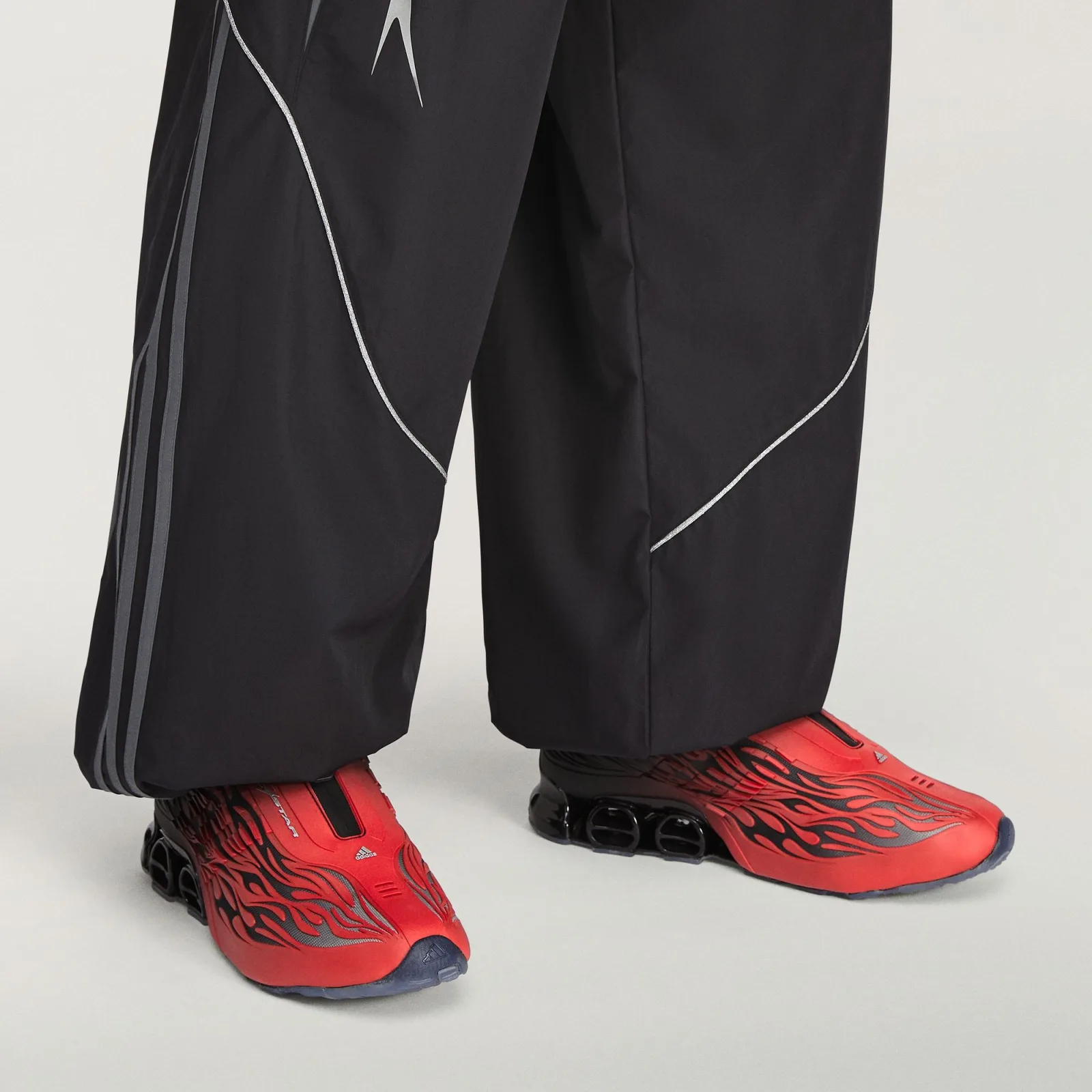 On-foot shot in black wide-leg trousers with grey side stripes and silver piping, Red/Black