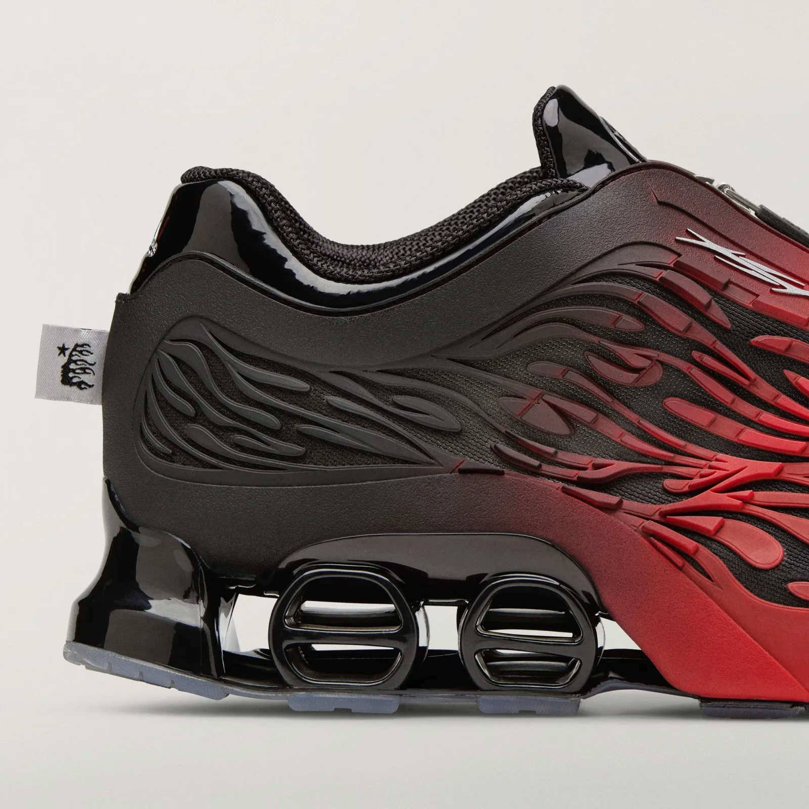 Close detail of heel and midsole, glossy black patent, flame ridges and white woven tag, Red/Black